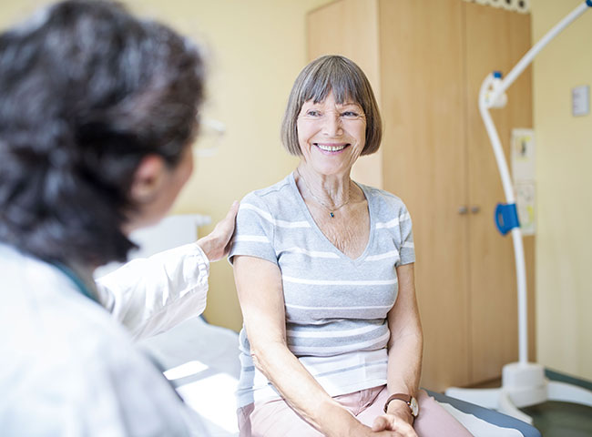 Eine Ärztin im Gespräch mit einer älteren Patientin im Krankenzimmer